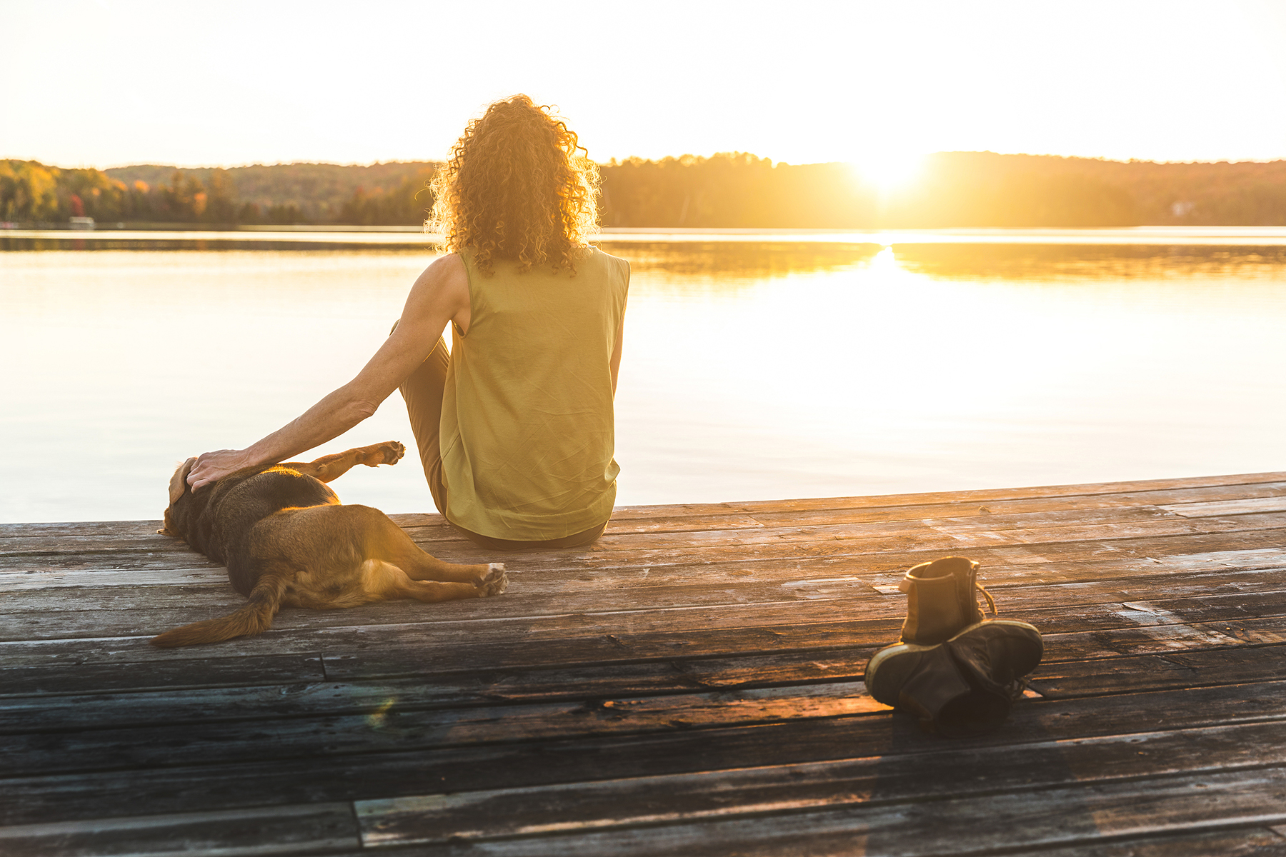 Woman And Dog Relaxing On The Dock At Sunset